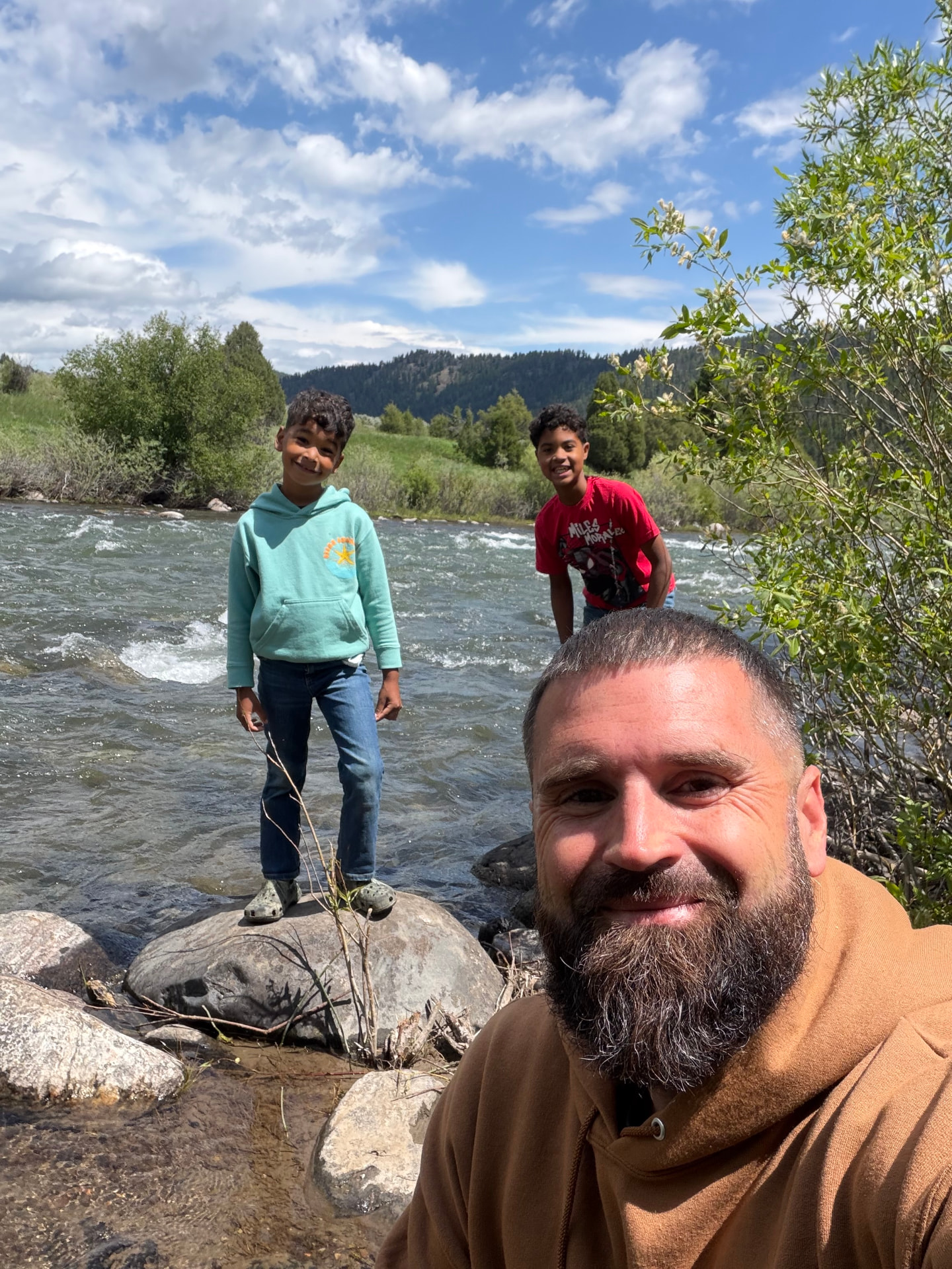 Antone Baillie with his two sons beside a mountain river